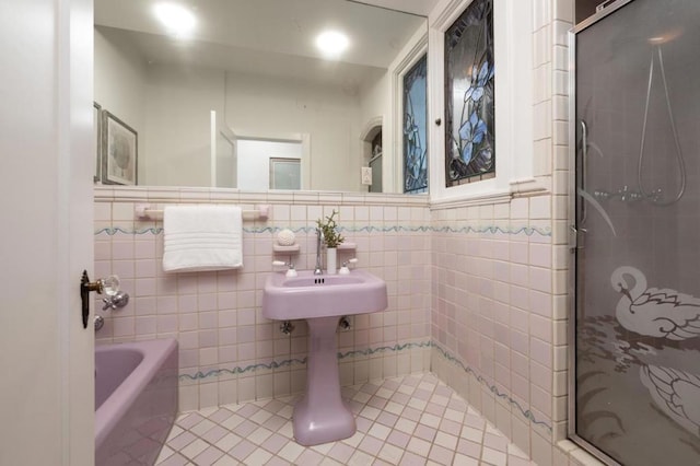 bathroom with tile patterned flooring, separate shower and tub, and tile walls