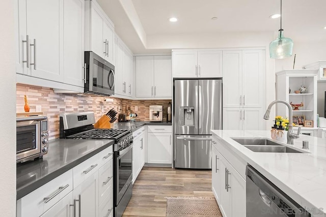 kitchen featuring white cabinetry, stainless steel appliances, tasteful backsplash, pendant lighting, and sink