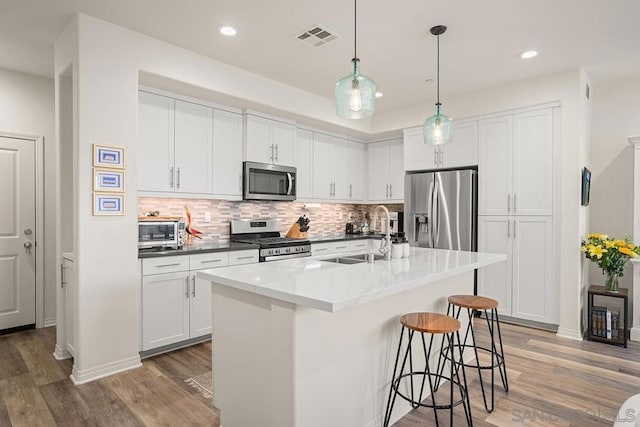 kitchen with a center island with sink, sink, stainless steel appliances, and white cabinetry