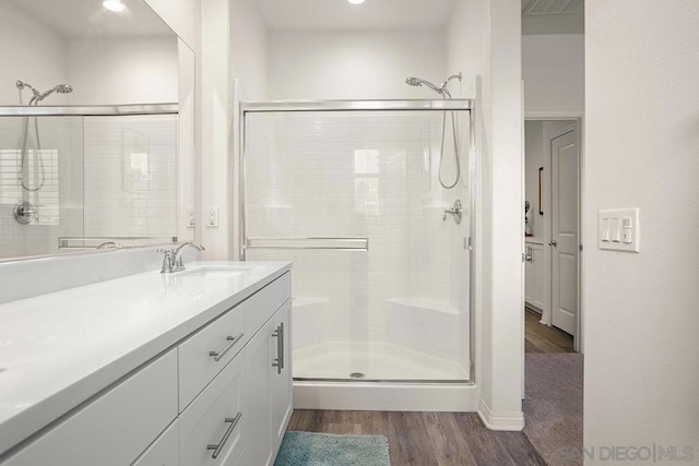 bathroom with hardwood / wood-style flooring, a shower with shower door, and vanity