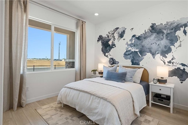 bedroom featuring light hardwood / wood-style floors and a water view