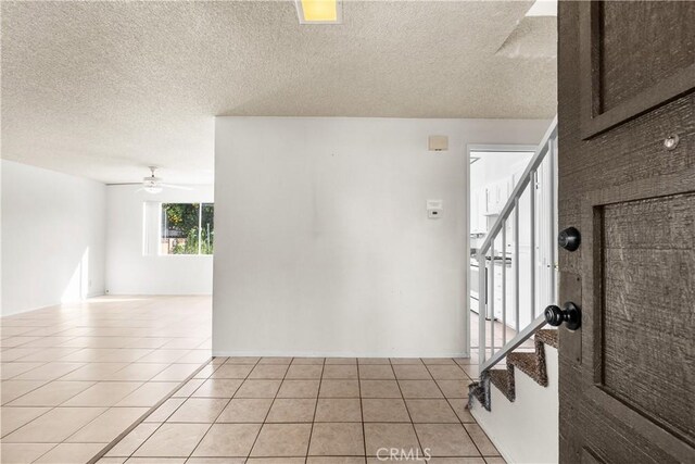 unfurnished room featuring a textured ceiling, ceiling fan, and light tile patterned floors