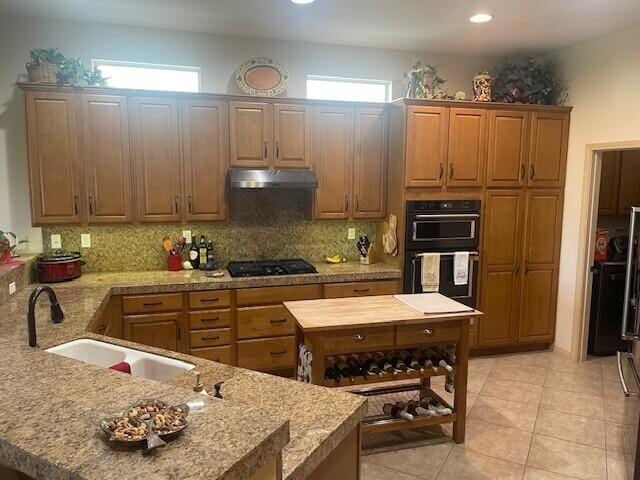 kitchen featuring light tile patterned floors, decorative backsplash, sink, and black appliances