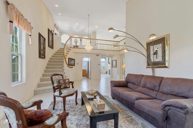 tiled living room featuring an inviting chandelier and a towering ceiling