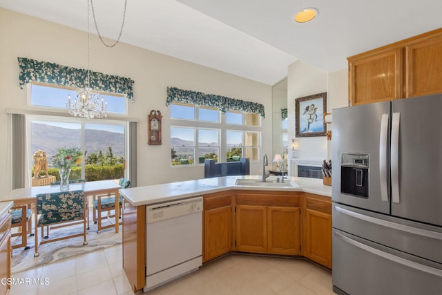 kitchen featuring sink, stainless steel fridge, a mountain view, a notable chandelier, and white dishwasher