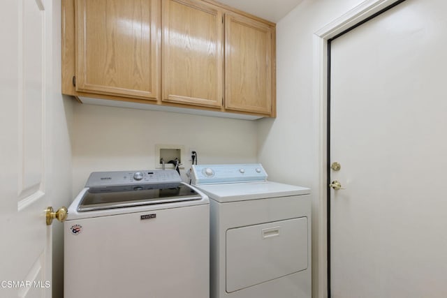 clothes washing area featuring cabinets and separate washer and dryer