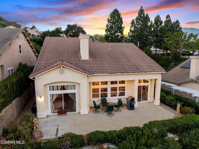 back house at dusk featuring a patio area