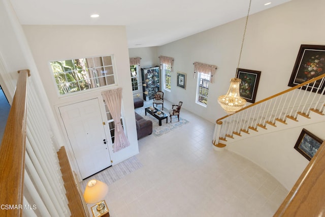 entryway with tile patterned flooring, a towering ceiling, and a chandelier