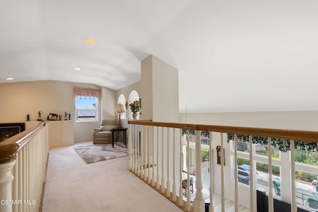 hall with lofted ceiling and light colored carpet