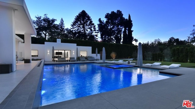 pool at dusk featuring an outdoor hangout area, a patio area, and a jacuzzi