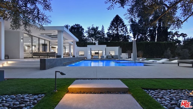 pool at dusk with a patio area