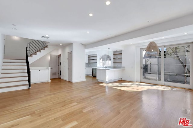 unfurnished living room with a healthy amount of sunlight, sink, and light hardwood / wood-style flooring