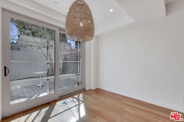 unfurnished dining area featuring hardwood / wood-style flooring and a raised ceiling