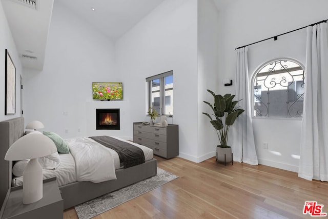 bedroom with a high ceiling and light hardwood / wood-style flooring