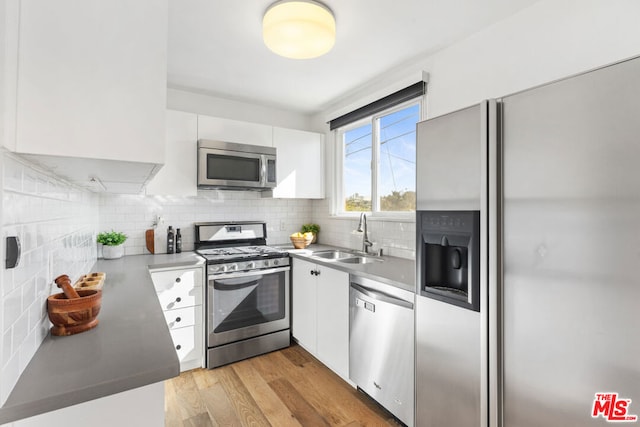 kitchen featuring tasteful backsplash, light hardwood / wood-style floors, sink, stainless steel appliances, and white cabinets