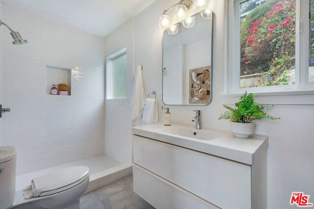 bathroom with plenty of natural light, toilet, vanity, and tile patterned flooring