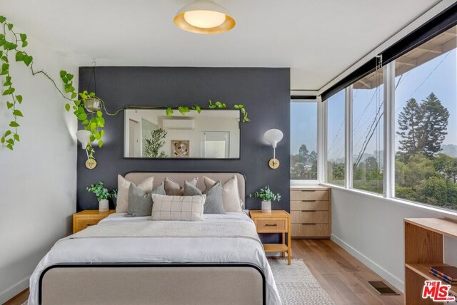 bedroom featuring a wall mounted AC and light hardwood / wood-style flooring