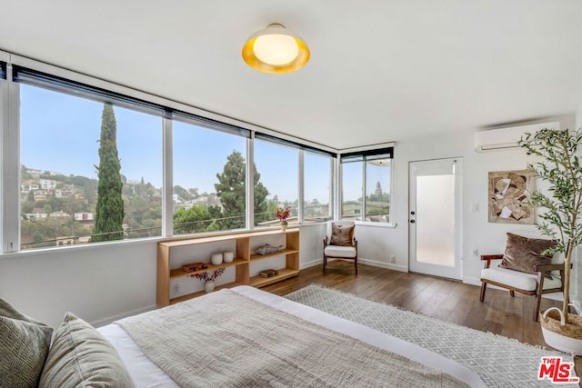 bedroom with an AC wall unit, dark hardwood / wood-style floors, and multiple windows