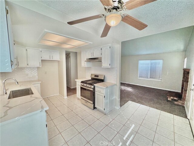 kitchen with light colored carpet, gas stove, white cabinets, and sink