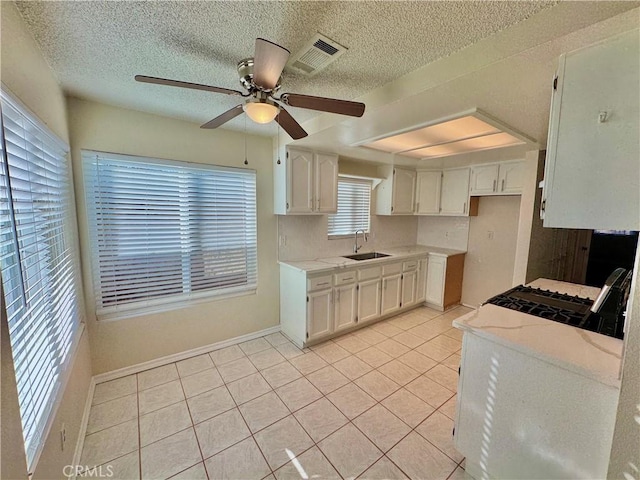 kitchen featuring ceiling fan, sink, light tile patterned floors, a textured ceiling, and white cabinets