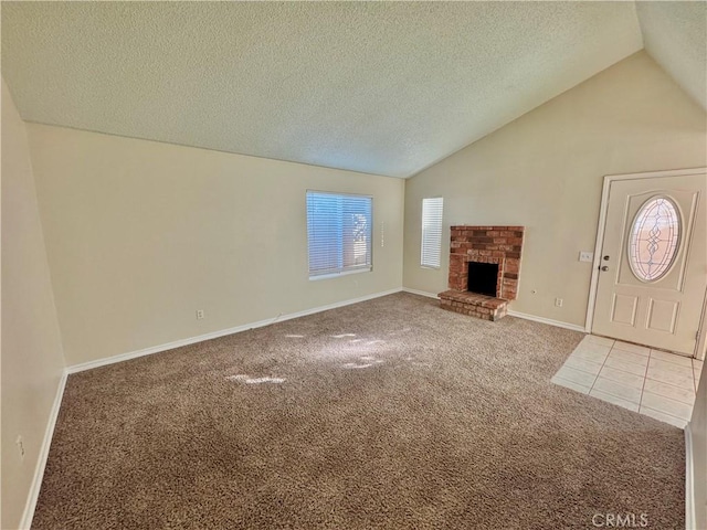 unfurnished living room featuring a textured ceiling, a brick fireplace, carpet flooring, and lofted ceiling