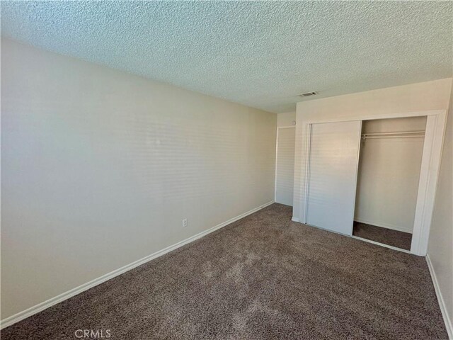 unfurnished bedroom with carpet, a closet, and a textured ceiling