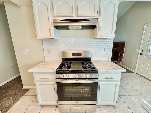 kitchen featuring light stone counters, white cabinets, range hood, and stainless steel range with gas stovetop