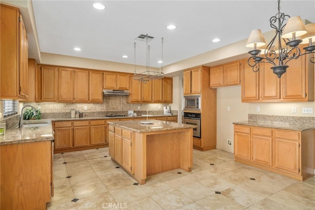 kitchen with pendant lighting, appliances with stainless steel finishes, a kitchen island, an inviting chandelier, and sink