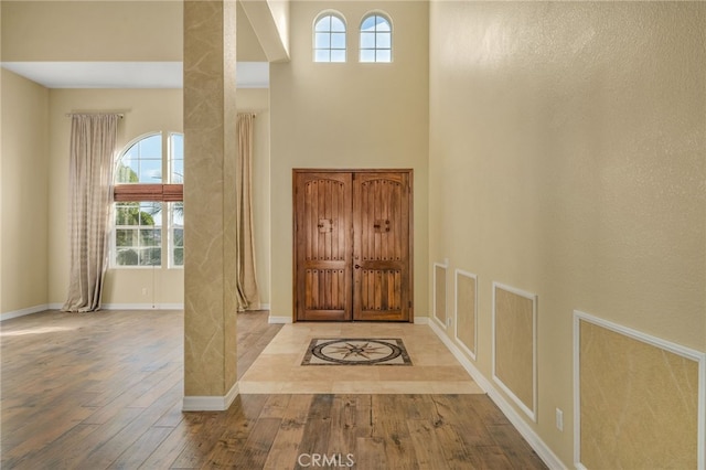 foyer featuring a healthy amount of sunlight, light hardwood / wood-style floors, and a high ceiling