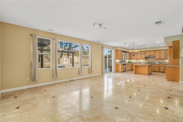 kitchen with decorative backsplash, hanging light fixtures, a chandelier, stainless steel dishwasher, and a center island