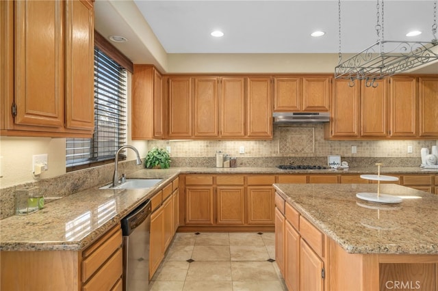 kitchen featuring a center island, stainless steel dishwasher, sink, black stovetop, and light stone counters