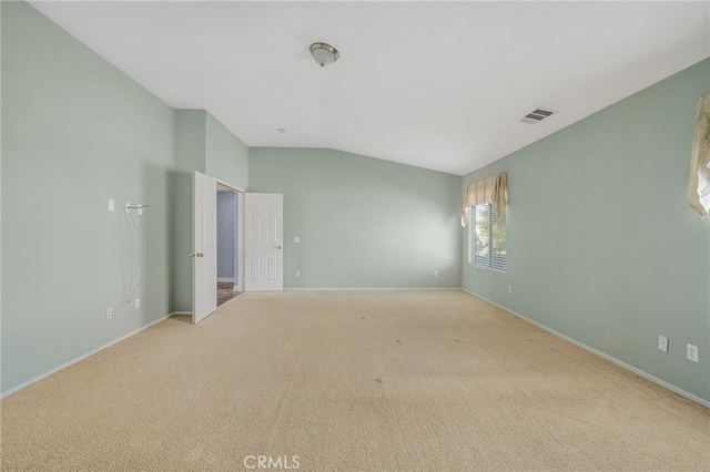 carpeted spare room featuring vaulted ceiling