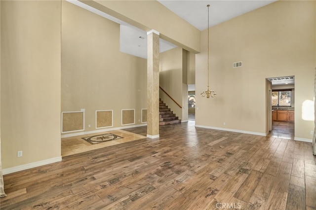 interior space with wood-type flooring, a towering ceiling, and an inviting chandelier