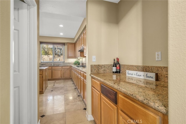 kitchen featuring light stone counters, sink, stainless steel gas stovetop, and light tile patterned flooring