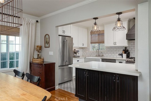 kitchen featuring light hardwood / wood-style floors, stainless steel appliances, backsplash, wall chimney exhaust hood, and white cabinets