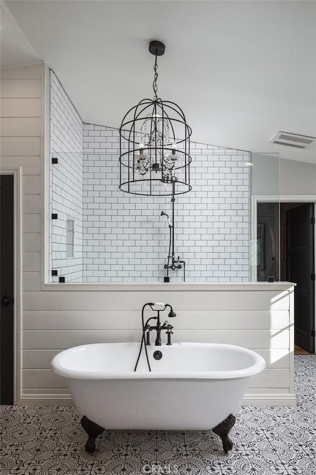 bathroom with a bathtub, vaulted ceiling, tile patterned floors, and a chandelier