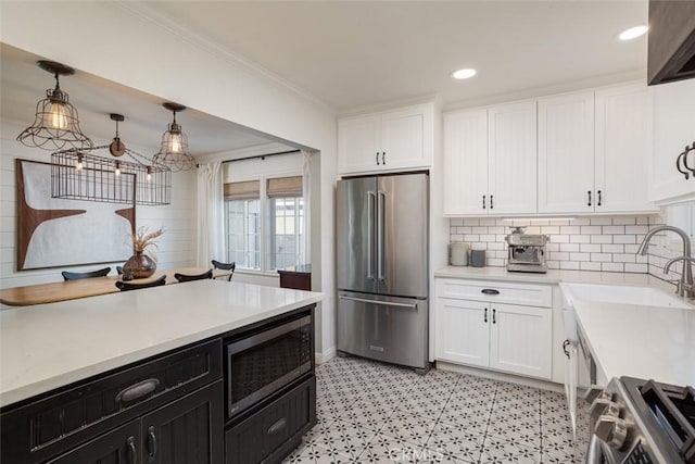 kitchen with high quality fridge, white cabinetry, hanging light fixtures, built in microwave, and range