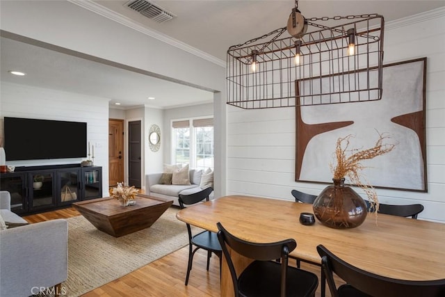 dining room featuring wood walls, ornamental molding, hardwood / wood-style floors, and a notable chandelier