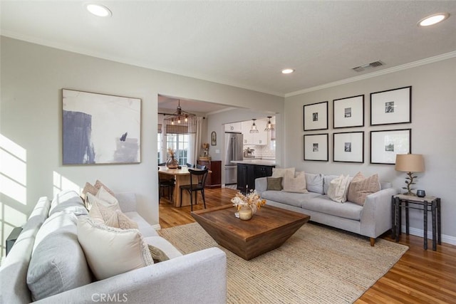 living room featuring a notable chandelier, crown molding, and light hardwood / wood-style floors