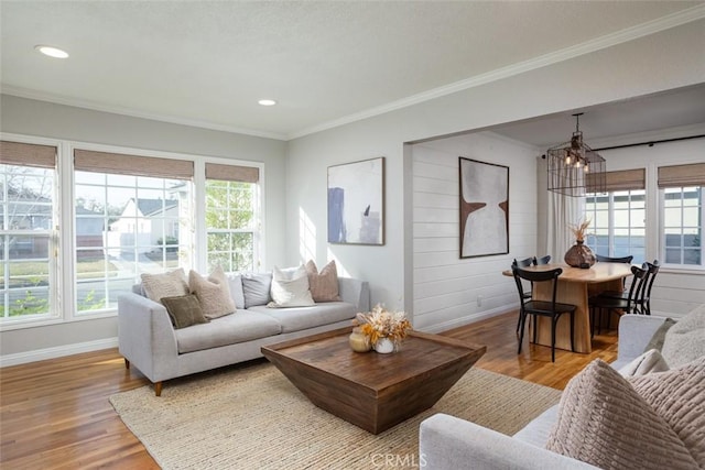 living room with hardwood / wood-style flooring, plenty of natural light, crown molding, and an inviting chandelier