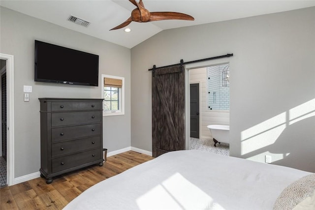 bedroom with lofted ceiling, light hardwood / wood-style floors, ceiling fan, ensuite bathroom, and a barn door