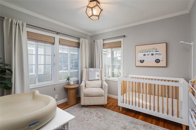 bedroom featuring crown molding, hardwood / wood-style floors, and a crib