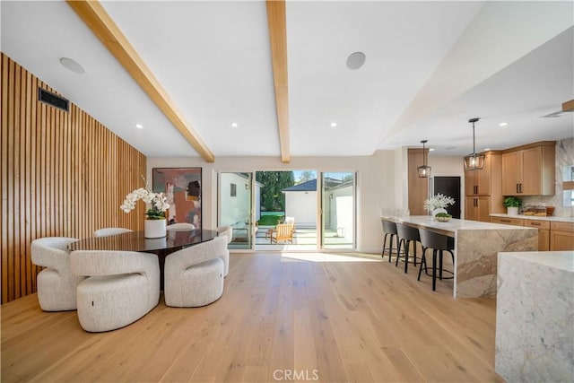 living room featuring beamed ceiling, wood walls, and light hardwood / wood-style floors