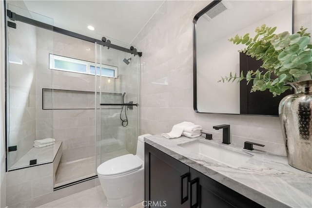 bathroom featuring tile walls, walk in shower, vanity, and toilet