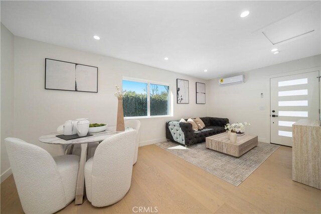 living room with light hardwood / wood-style flooring and a wall mounted air conditioner