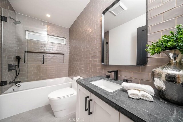 full bathroom featuring tasteful backsplash, vanity, tile walls, toilet, and tiled shower / bath