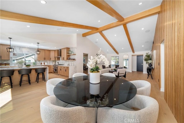 dining room featuring beam ceiling, high vaulted ceiling, and light hardwood / wood-style floors