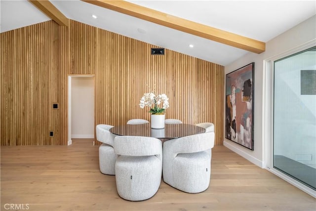 dining area featuring vaulted ceiling with beams, light wood-type flooring, and wood walls