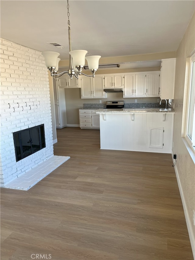 kitchen with stainless steel range with electric stovetop, decorative light fixtures, kitchen peninsula, and white cabinets