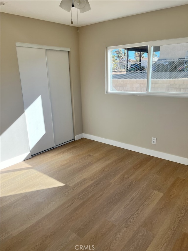 unfurnished bedroom with light hardwood / wood-style floors, a closet, and ceiling fan